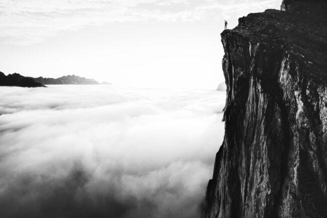 Traveler,Standing,On,Cliff,Edge,Mountain,Top,Above,Sunset,Clouds