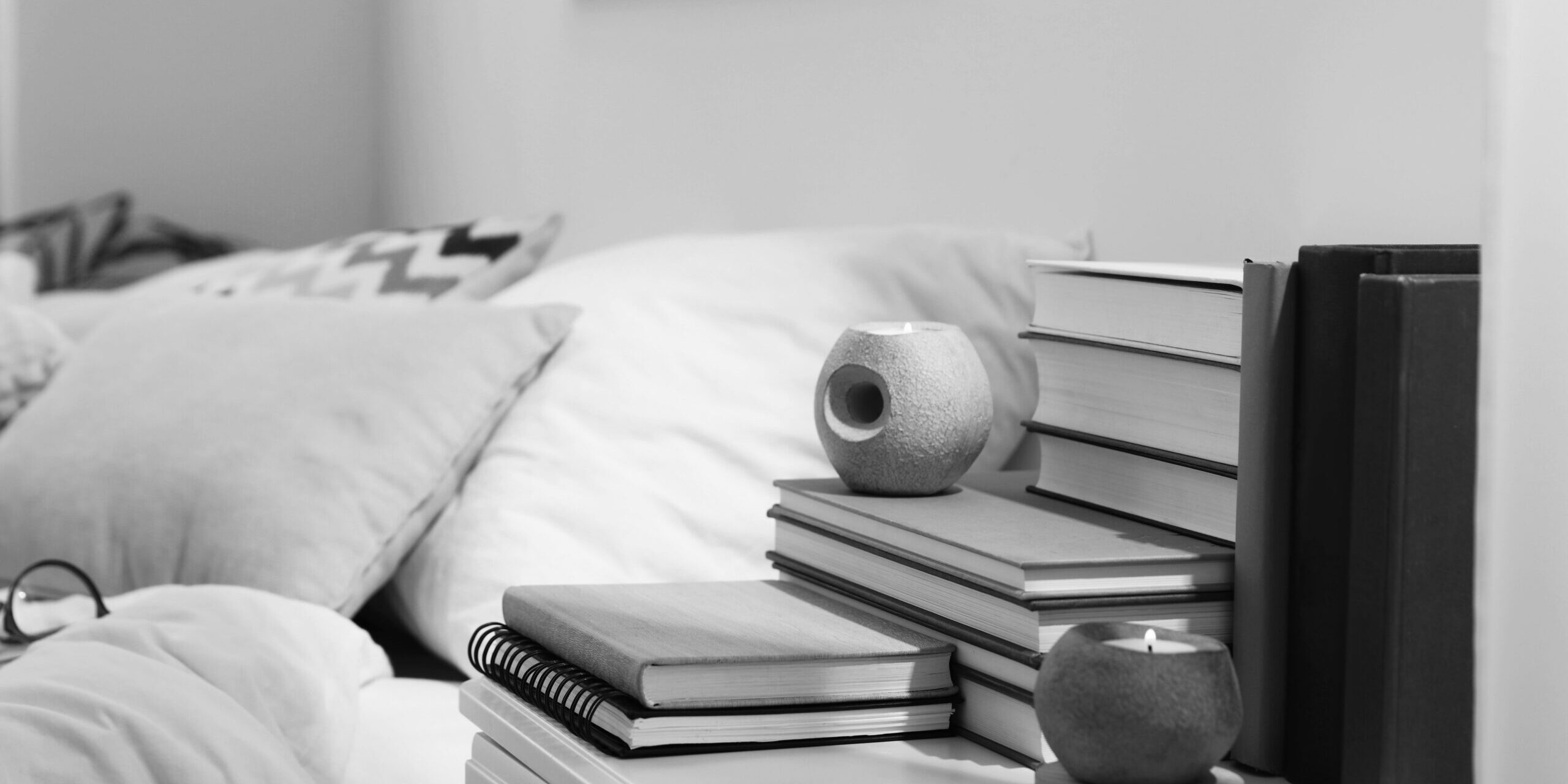 Hardcover,Books,And,Scented,Candles,On,White,Bedside,Table,In
