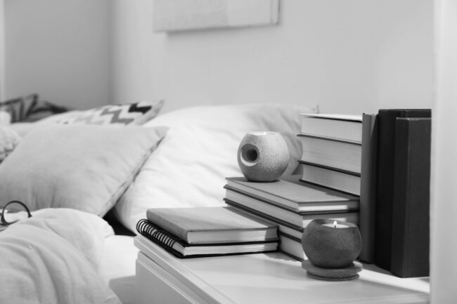 Hardcover,Books,And,Scented,Candles,On,White,Bedside,Table,In