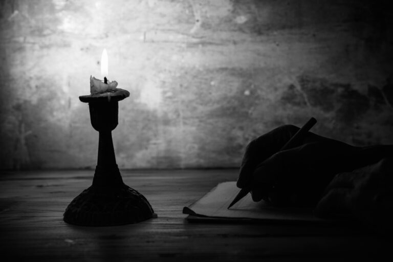 Hand,Writing,Letter,With,Pencil,On,Paper,In,Candle,Light